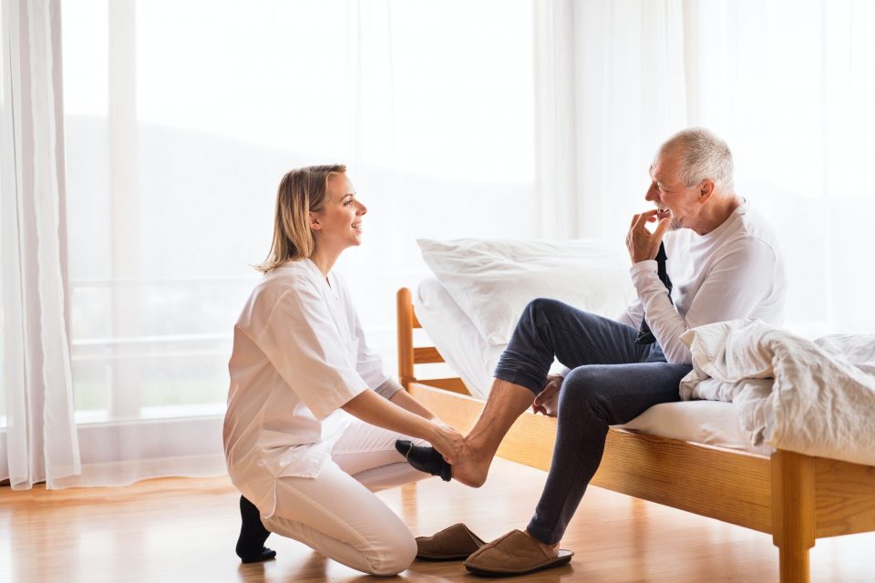 Health visitor and senior man during home visit.